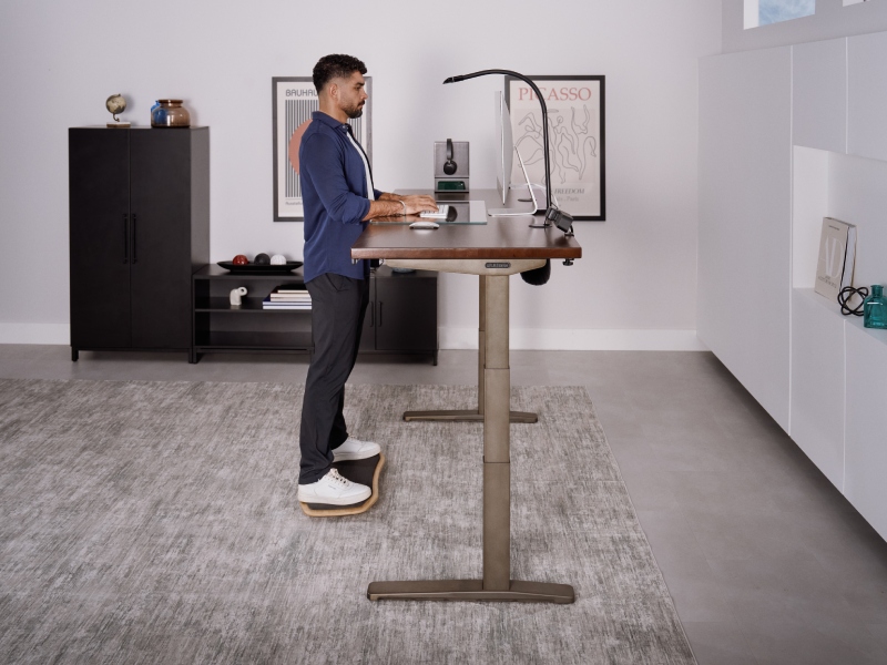 Person working at a standing desk on a bamboo motion-x board